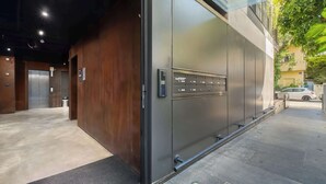 Une entrée moderne, avec une grande porte en métal, un mur en bois et un sol carrelé.