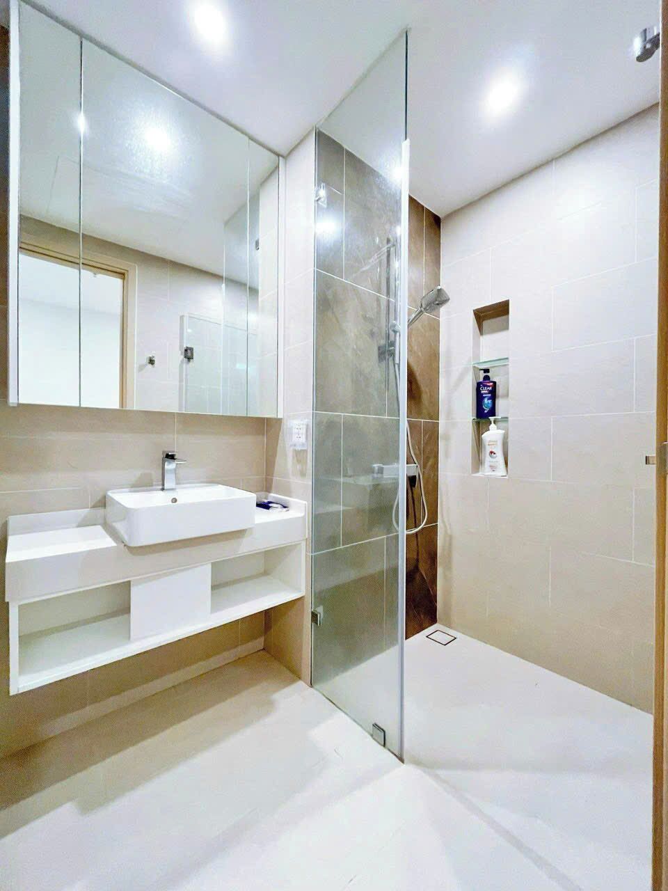 Un baño moderno con cabina de ducha de vidrio, un lavabo blanco y un espejo.