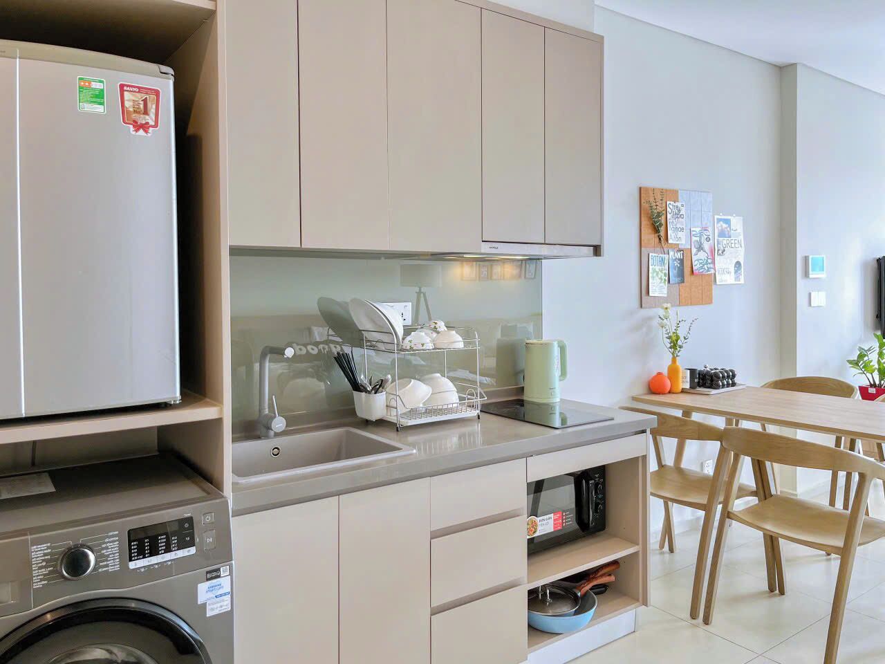 Cocina compacta con lavadora, lavaplatos y zona de comedor con sillas.