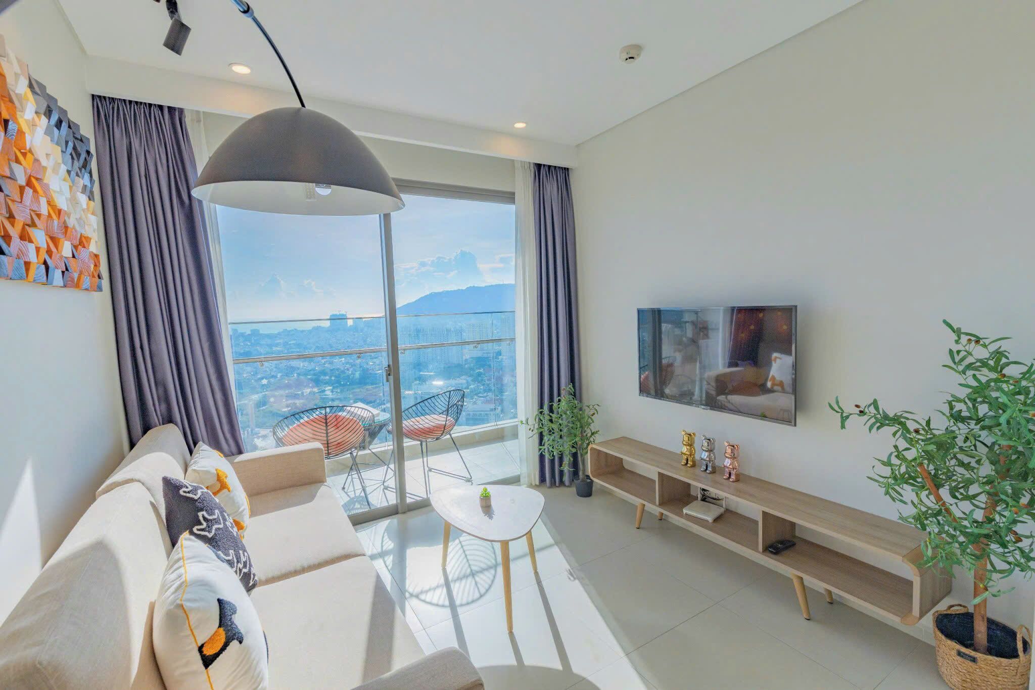 Un soggiorno moderno con un divano, un tavolino, una TV e un balcone con vista.