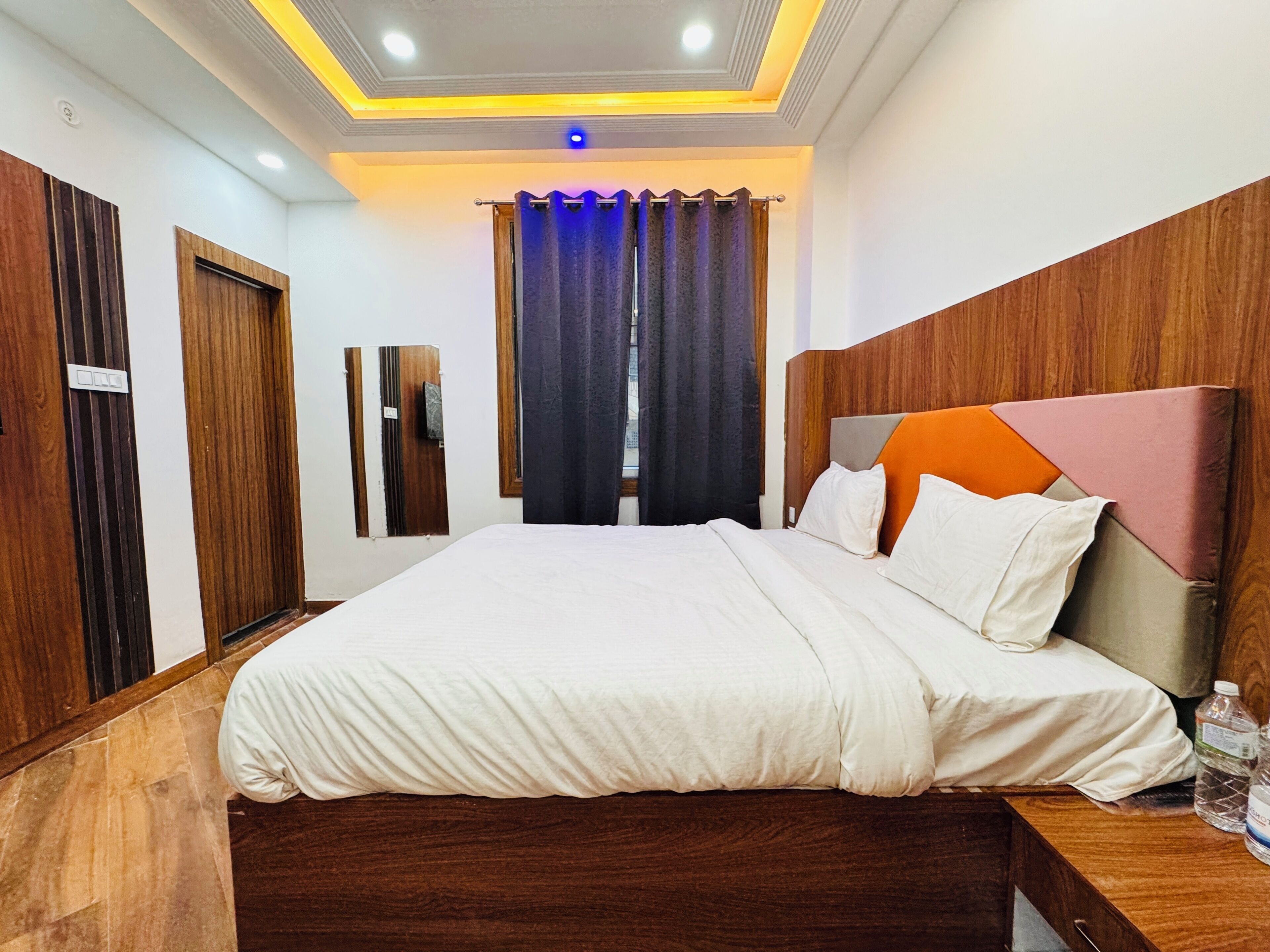 Un dormitorio con una cama, cabecera de madera, cortinas y una lámpara en el techo.