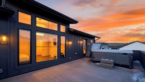 Een modern gebouw met grote ramen, een terras en een jacuzzi.