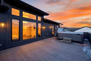 Ein modernes Gebäude mit großen Fenstern, einer Terrasse und einem Whirlpool.