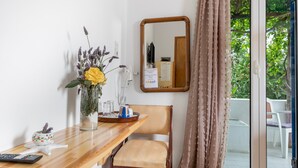 A wooden table with a vase of flowers, a remote control, and a decorative item. A chair is positioned at the table, and a mirror hangs on the wall. - Room 2 at Pagali Hotel with Garden View (Órmos Aiyialís)