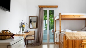 A room with a bunk bed, a desk with a basket, a chair, a mirror, and a sliding glass door leading to an outdoor area. - Room 2 at Pagali Hotel with Garden View (Órmos Aiyialís)