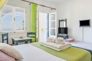 Habitación de hotel con cama, escritorio, silla, televisión y vista al mar.