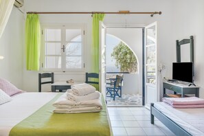 Une chambre avec un lit, un bureau, une chaise, une télévision et un balcon avec vue.