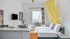 Een hotelkamer met een bed, een televisie, een bureau en een balkon met uitzicht.