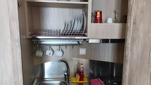 Eine kleine Küche mit Spüle, Herd und Holzschränken.