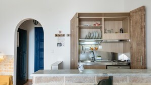 A kitchen with a stone countertop, wooden cabinets, and a blue door. - Room 15 at Pagali Hotel with King Bed (Órmos Aiyialís)