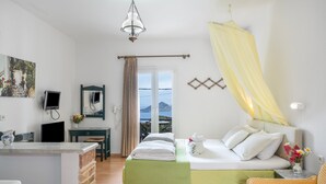 A bedroom with a bed, a desk, a chair, a mirror, and a view of the outdoors. - Room 15 at Pagali Hotel with King Bed (Órmos Aiyialís)