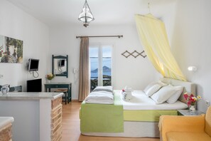 Ein Schlafzimmer mit Bett, Schreibtisch, Stuhl, Spiegel und Blick ins Freie.
