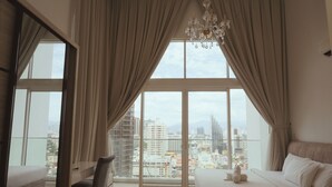 Ein Schlafzimmer mit großem Fenster, einem Bett, einem Sessel und einer Deckenleuchte.