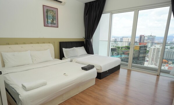 Ein Hotelzimmer mit zwei Betten, einem großen Fenster mit Blick auf die Stadt und einem gerahmten Bild an der Wand.