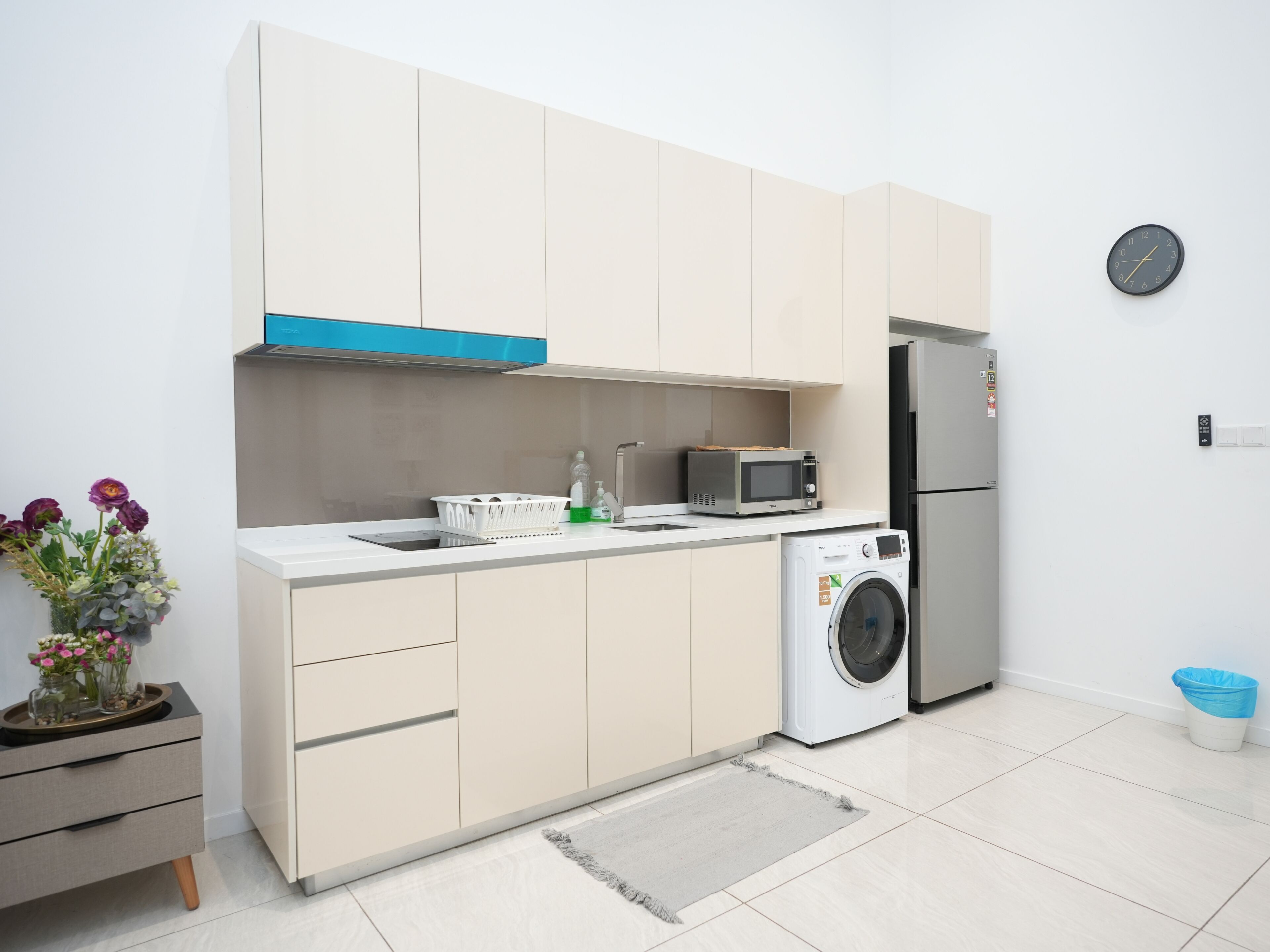 Eine moderne Küche mit Waschmaschine, Mikrowelle und Kühlschrank.