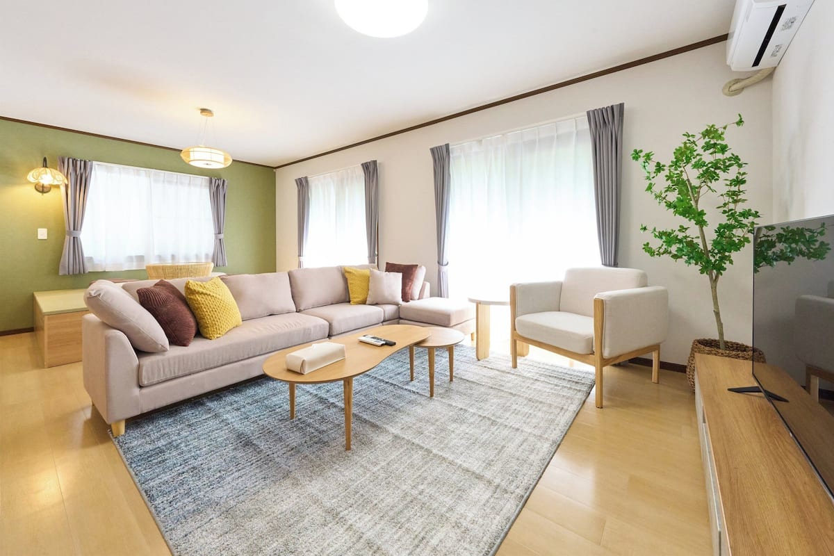 A modern living room with a sofa, armchair, coffee table, and a potted plant.