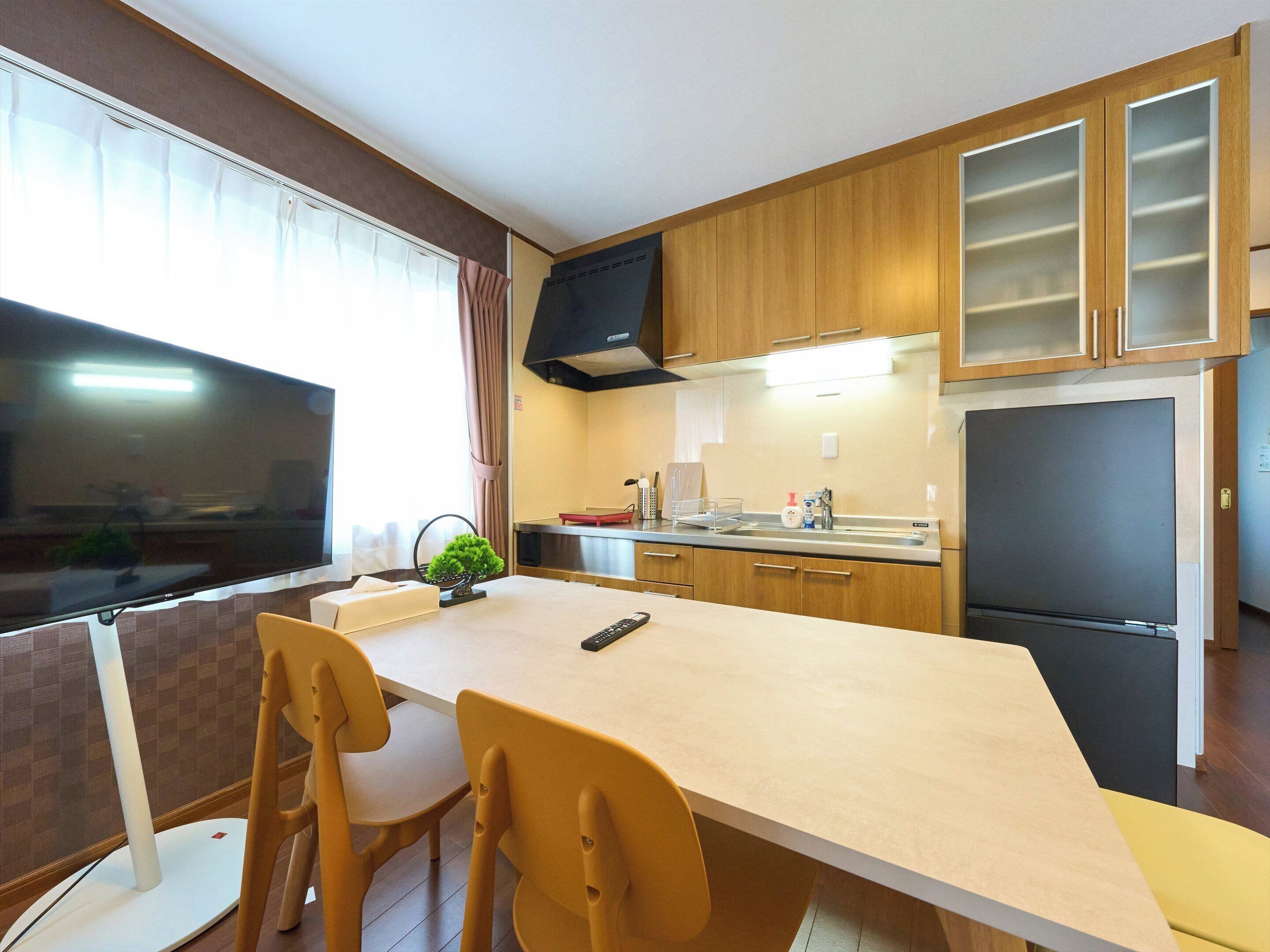 A modern kitchen with wooden cabinets, a black refrigerator, and a dining area with a table and chairs.