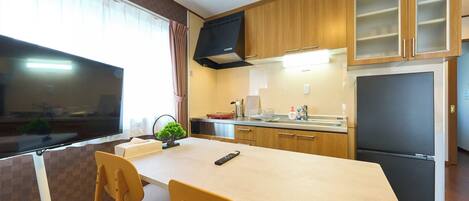 A modern kitchen with wooden cabinets, a black refrigerator, and a dining area with a table and chairs.
