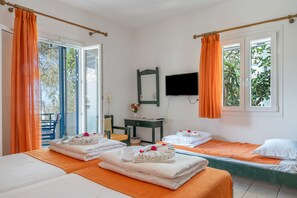 Habitación de hotel con dos camas, un escritorio, una silla, un televisor y un balcón con cortinas naranjas.