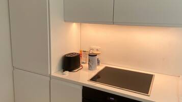 Eine kompakte Küche mit einem integrierten Geschirrspüler, einem Toaster und einem Wasserkocher auf der Arbeitsfläche.