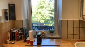 A kitchen with a window, a coffee menu, kitchen utensils, and a sink. - Cozy Apartment in Hannover – Near City, Fair, MHH with Balcony and Wi-Fi (Hannover)