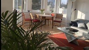 A bright living room with large windows, a glass coffee table, and a sofa. - Cozy Apartment in Hannover – Near City, Fair, MHH with Balcony and Wi-Fi (Hannover)