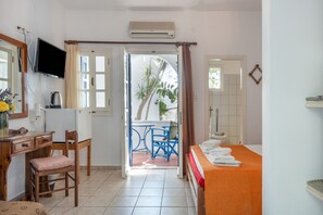 A room with a bed, a desk, a chair, a TV, and a bathroom. - Room 12 at Pagali Hotel in Amorgos (Órmos Aiyialís)