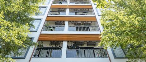 Ein mehrgeschossiges Gebäude mit Balkonen, Fenstern und einer Holzfassade.