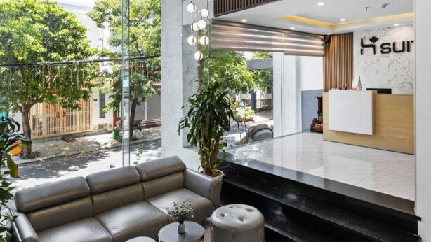 Uma área de recepção moderna com sofá, pufes e balcão de atendimento.