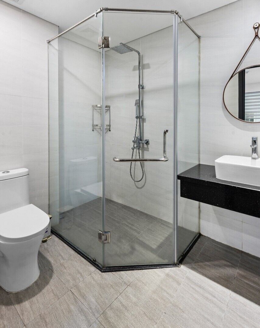 A modern bathroom with a glass-enclosed shower, a white toilet, and a black countertop with a sink.
