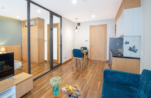 Ein modernes Hotelzimmer mit Fernseher, Essbereich und einer Küchenzeile.