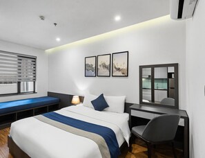 Une chambre d’hôtel moderne équipée d’un lit, d’une table de chevet, d’une chaise et offrant une vue sur la cuisine.
