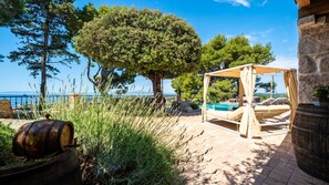 A patio with a wooden swing, a stone barrel, and a view of the sea. - Vila Pantovcak with stunning views by Villas Guide (Mundanije)