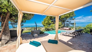 A covered outdoor area with a pool, lounge chairs, and a view of the sea. - Vila Pantovcak with stunning views by Villas Guide (Mundanije)