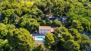 An aerial view of a house surrounded by dense trees, with a swimming pool in the foreground. - Vila Pantovcak with stunning views by Villas Guide (Mundanije)