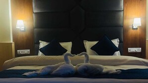 Ett hotellrum med en stor säng, två väggmonterade lampor och en dekorativ sänggavel formad som en svan.
