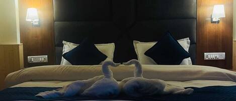 Una habitación de hotel con una cama grande, dos lámparas fijadas a la pared y un cabecero decorado con la figura de un cisne.