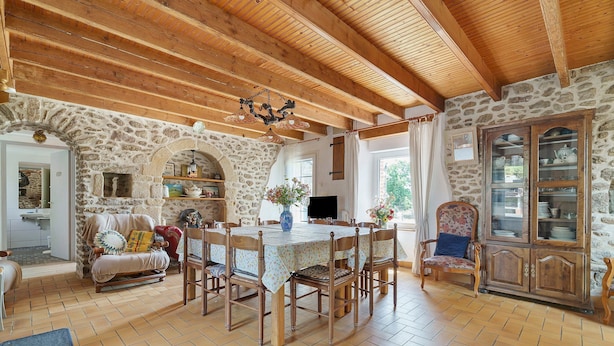 A rustic dining area with a stone wall, wooden ceiling beams, and a tiled floor. - Holiday Home 'Gite Renouard' with Private Garden, Wi-Fi and Air Conditioning (Saint-Cast-le-Guildo)