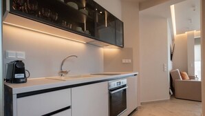 A modern kitchen with a built-in oven, a coffee maker, and a sink. - Althea Suites 4 by Rentals Pro - Nea Moudania Halkidiki (Nea Moudania)