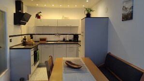 A compact kitchen with a dining area, a built-in oven, and a coffee maker. - Apartment 'Fewo Im Grünen Near Listertalsperre' with Private Terrace & Wi-Fi (Meinerzhagen)