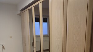 A room with a wooden floor, a large wardrobe with mirrored doors, and a radiator on the wall. - Apartment 'Fewo Im Grünen Near Listertalsperre' with Private Terrace & Wi-Fi (Meinerzhagen)