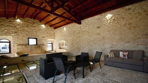 Un intérieur rustique avec des murs en pierre, un plafond en bois, une table à manger avec des chaises et un canapé.