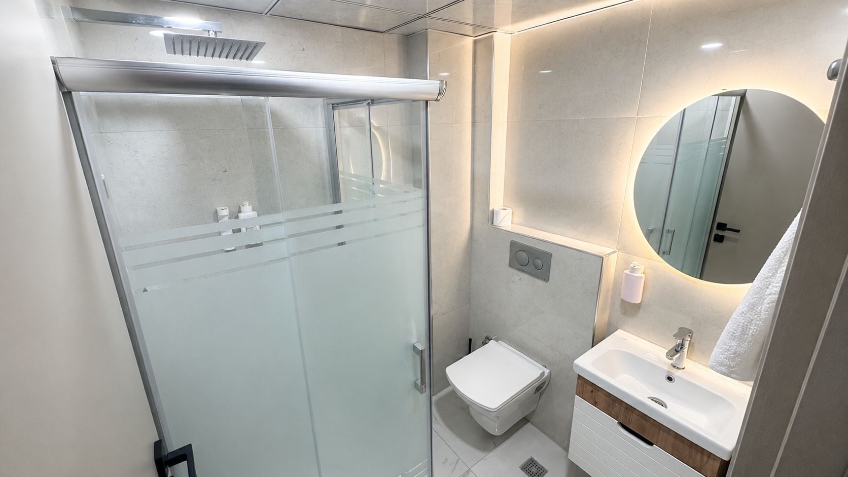 Un bagno moderno con cabina doccia in vetro, un water e un lavandino con specchio sopra.