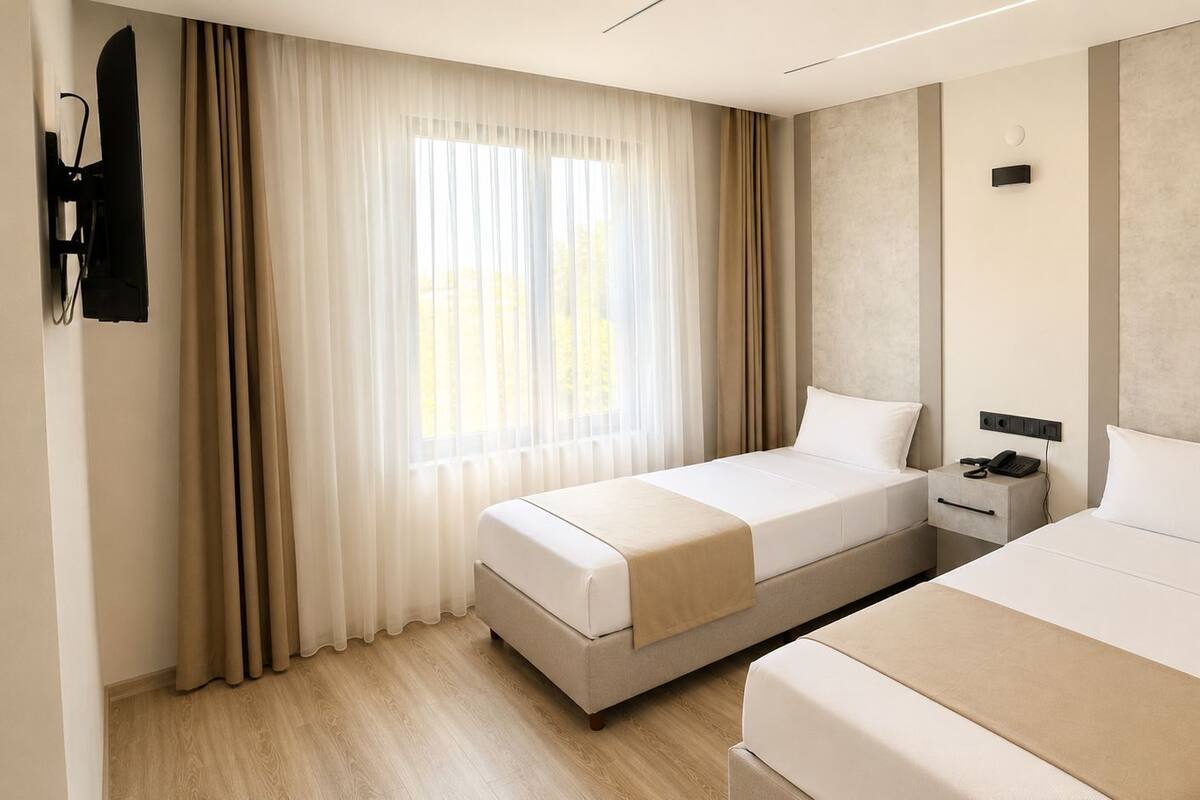 Ein Hotelzimmer mit zwei Betten, einem Nachttisch mit Telefon und einem wandmontierten Fernseher.