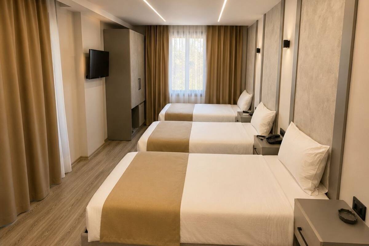Ein Hotelzimmer mit zwei Betten, einem Fernseher und einem großen Fenster mit Vorhängen.