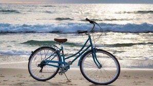 Ein Fahrrad am Strand, im Hintergrund Wellen.