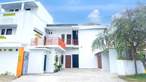 Un bâtiment à deux étages, doté d’un toit plat, d’un balcon à l’étage supérieur et d’une porte avec une enseigne.
