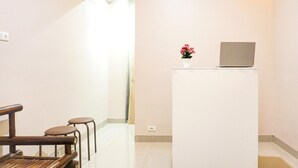 Une pièce avec un bureau blanc, un ordinateur portable et une petite plante en pot.