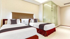 A hotel room with two beds, a glass wardrobe, and a modern design.