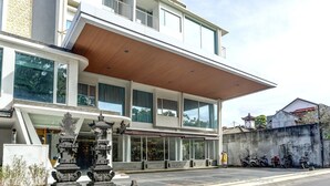 A modern building with large windows, a covered entrance, and a parking area with motorcycles.